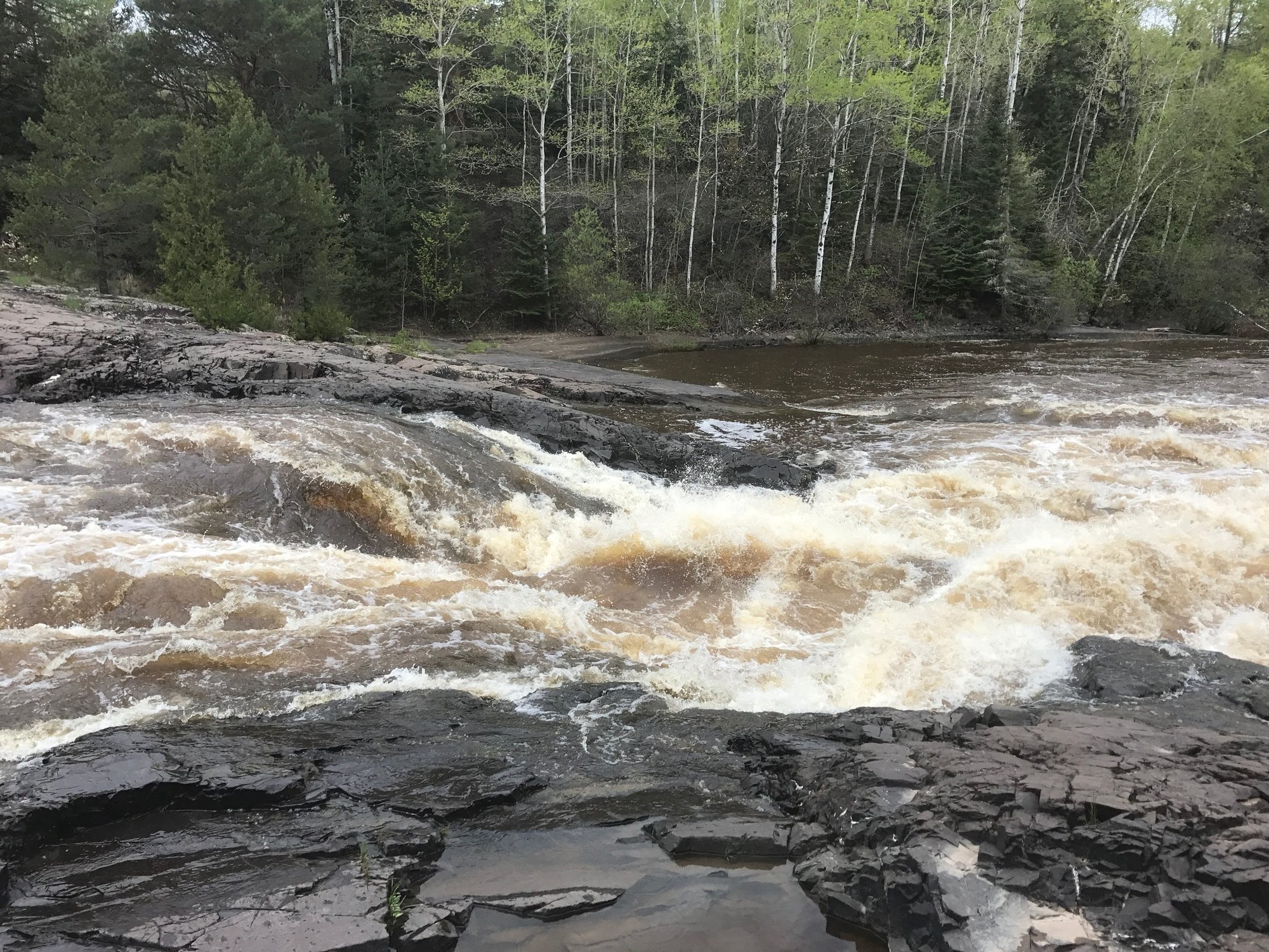 Fast river rapids rushing over dark rock