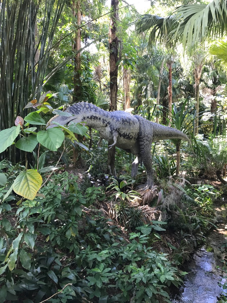 Dinosaur reconstruction standing in a lush tropical environment